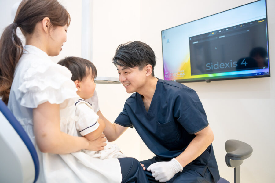 診療の様子。保護者に抱っこされながら診察を受けるこども。